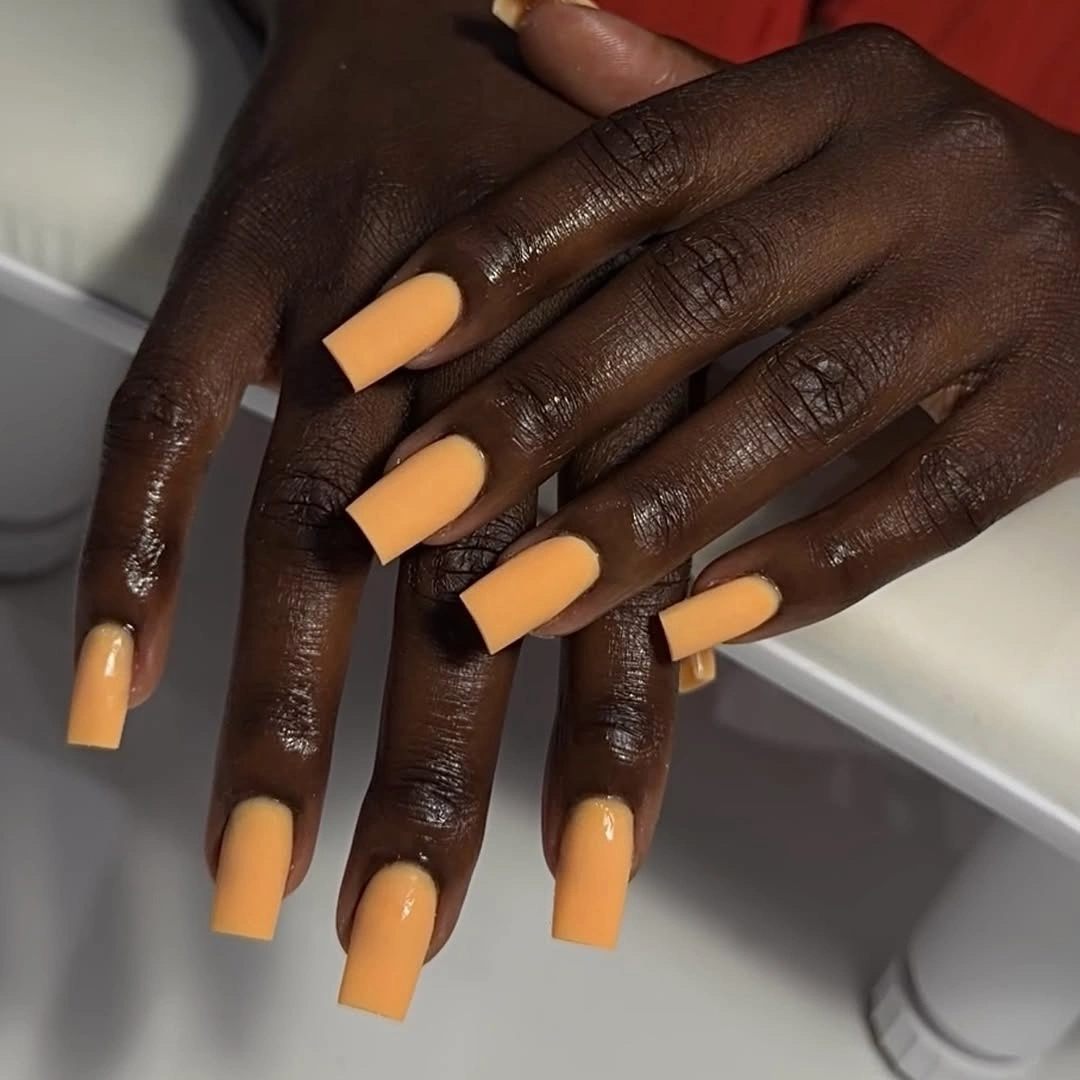 Long square nails with warm peach-orange polish