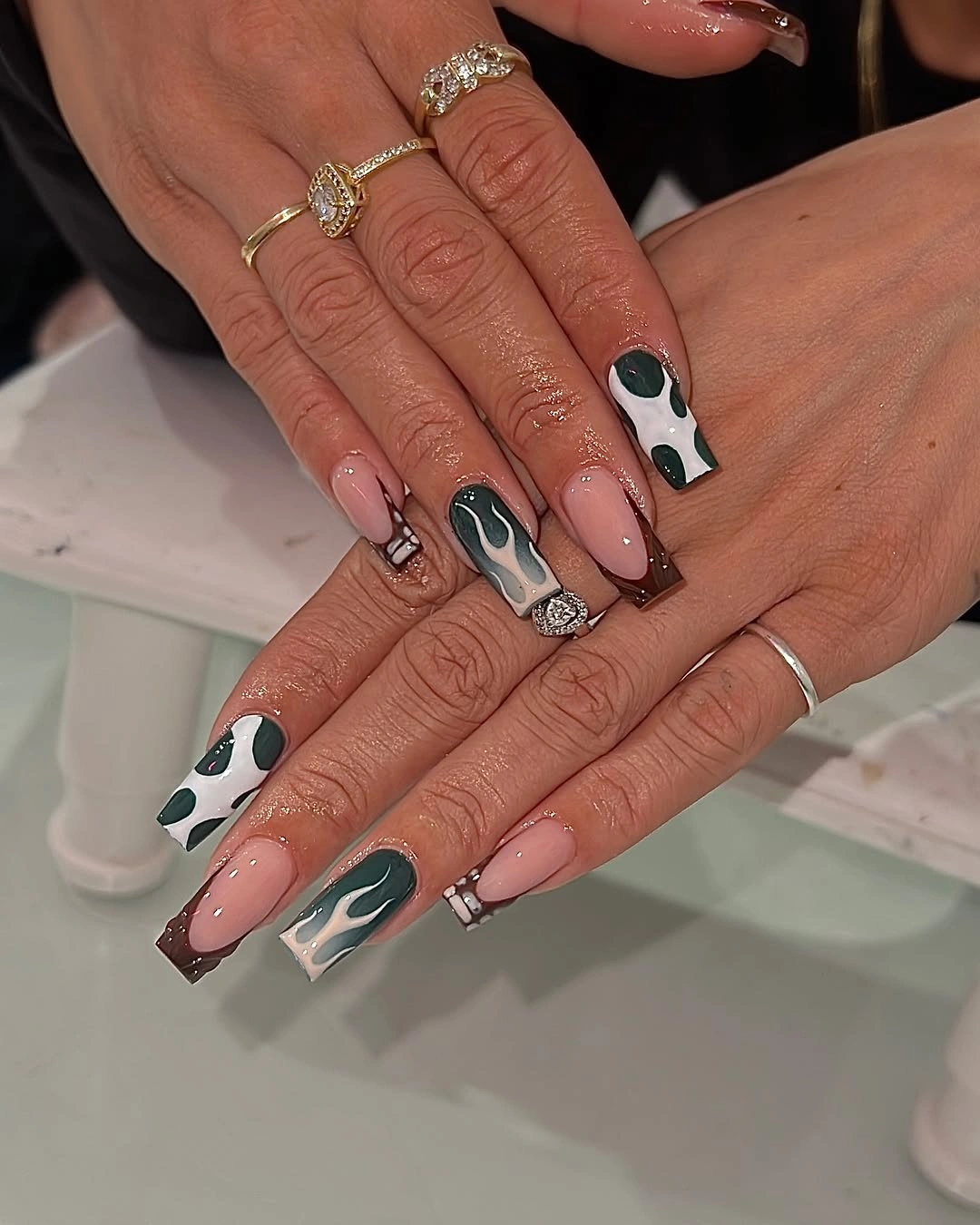 Dark green patterned nails with brown French tips