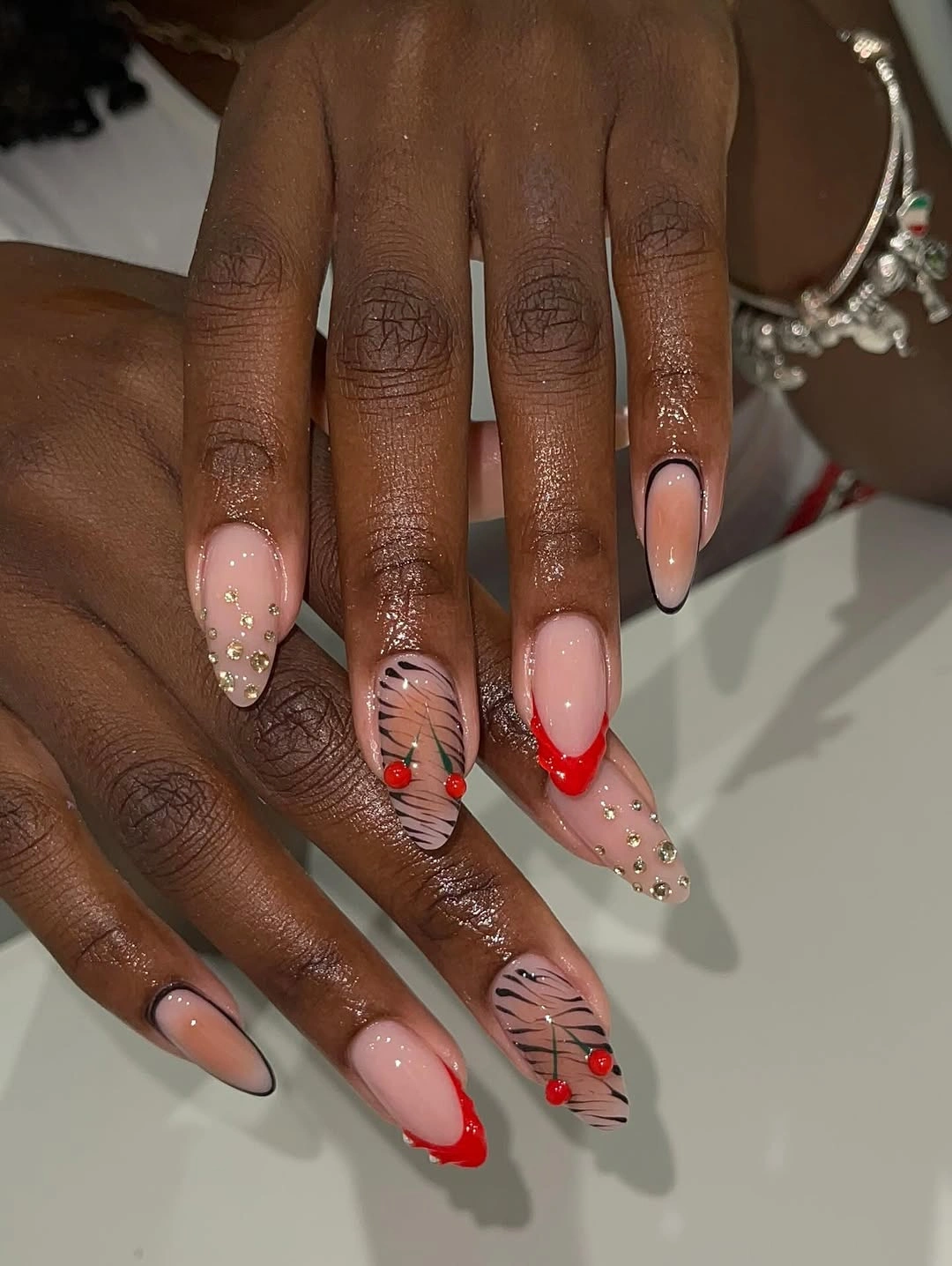 Long nude nails with red tips and black accents