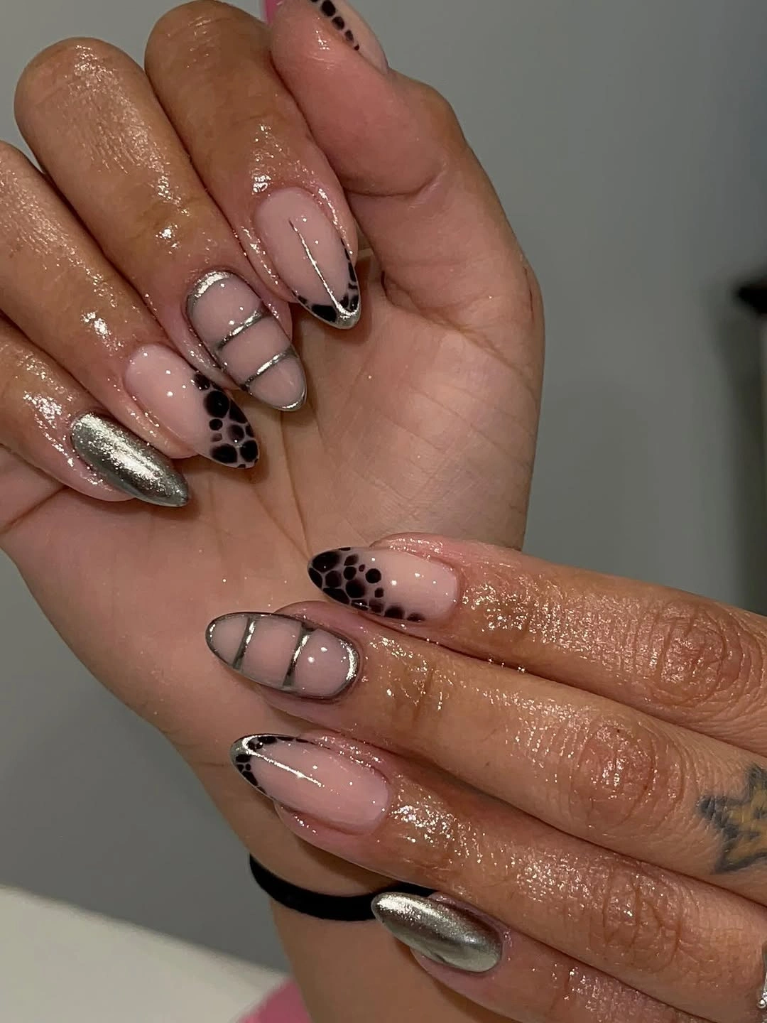 Almond nails with black patterned tips and silver accents