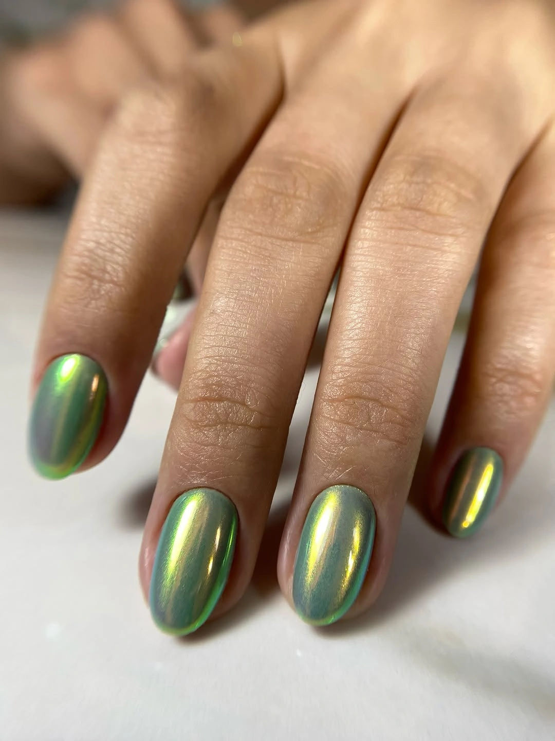 Short oval nails with reflective green gold color shift