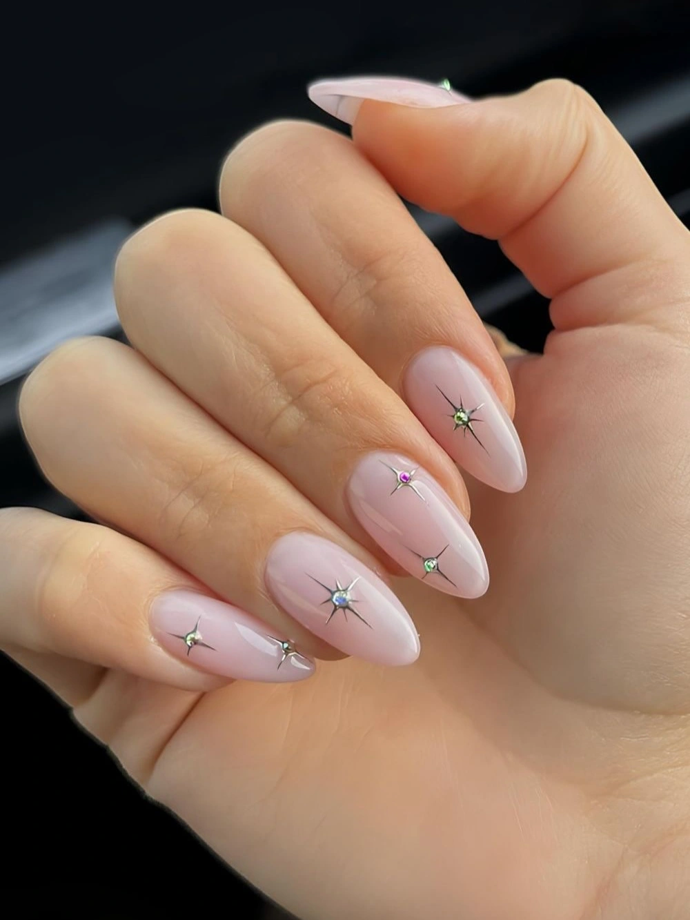 Long blush almond nails with tiny silver star like accents