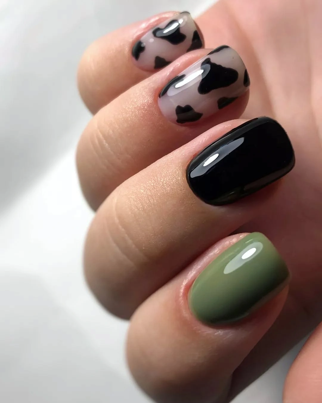 Black cream spotted nails with one muted olive accent