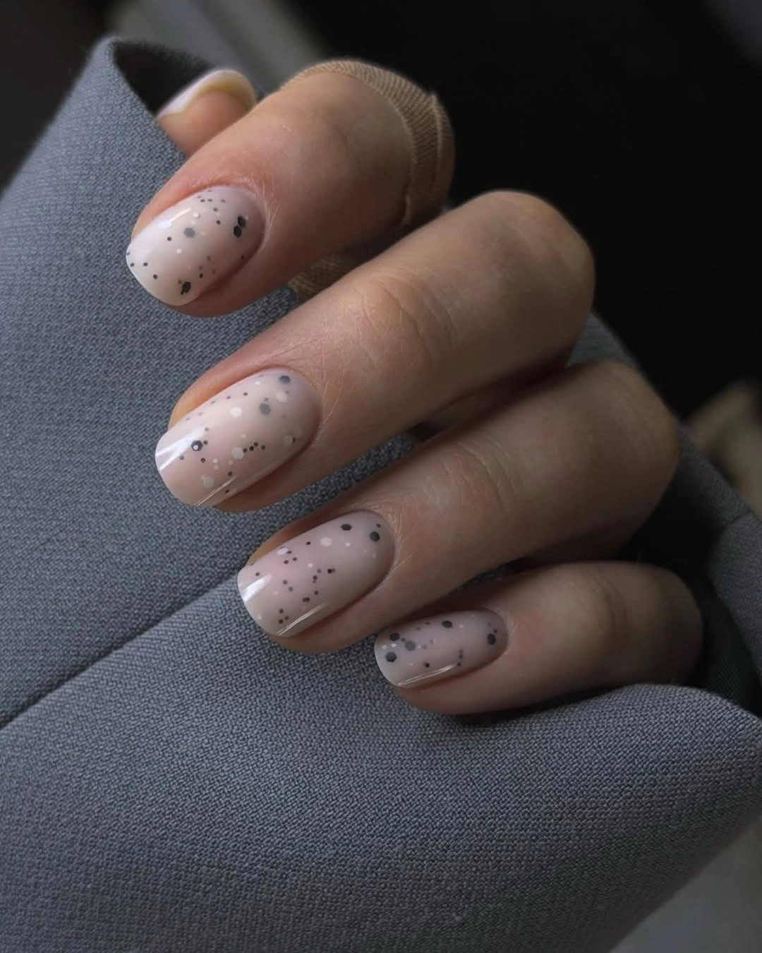 Pale nude almond nails with sparse dark speckles