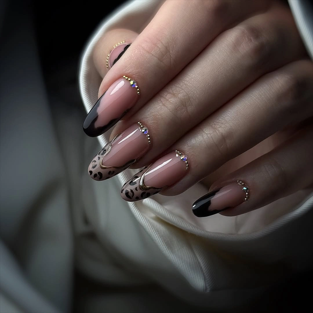 Medium nude almond nails with black tips and fine gold lines