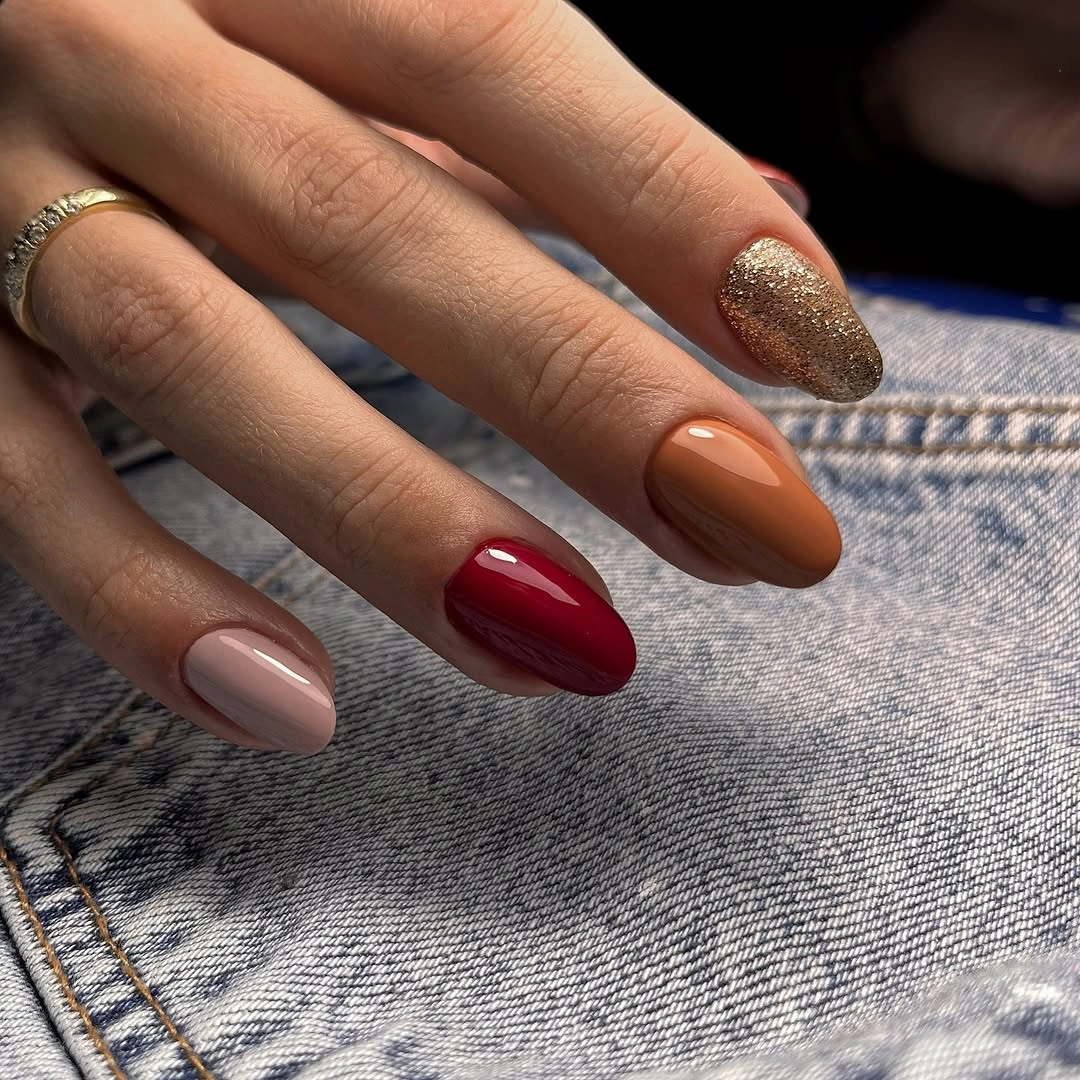 Medium almond nails mixing nude warm red and gold sparkle