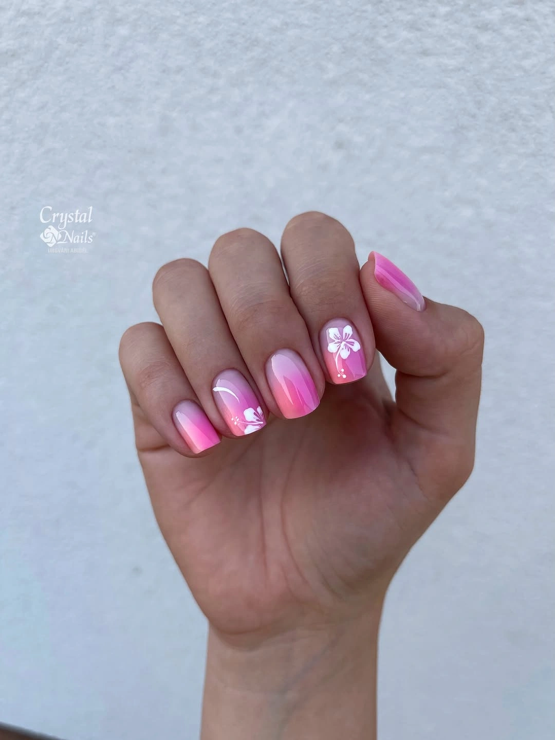 Short pink nails with brighter tips and a small floral accent