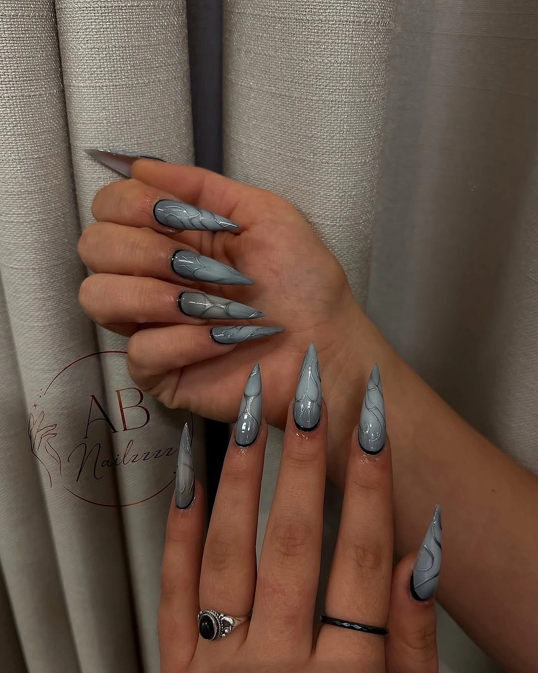 Long pointed silver gray nails with dark curved line motifs