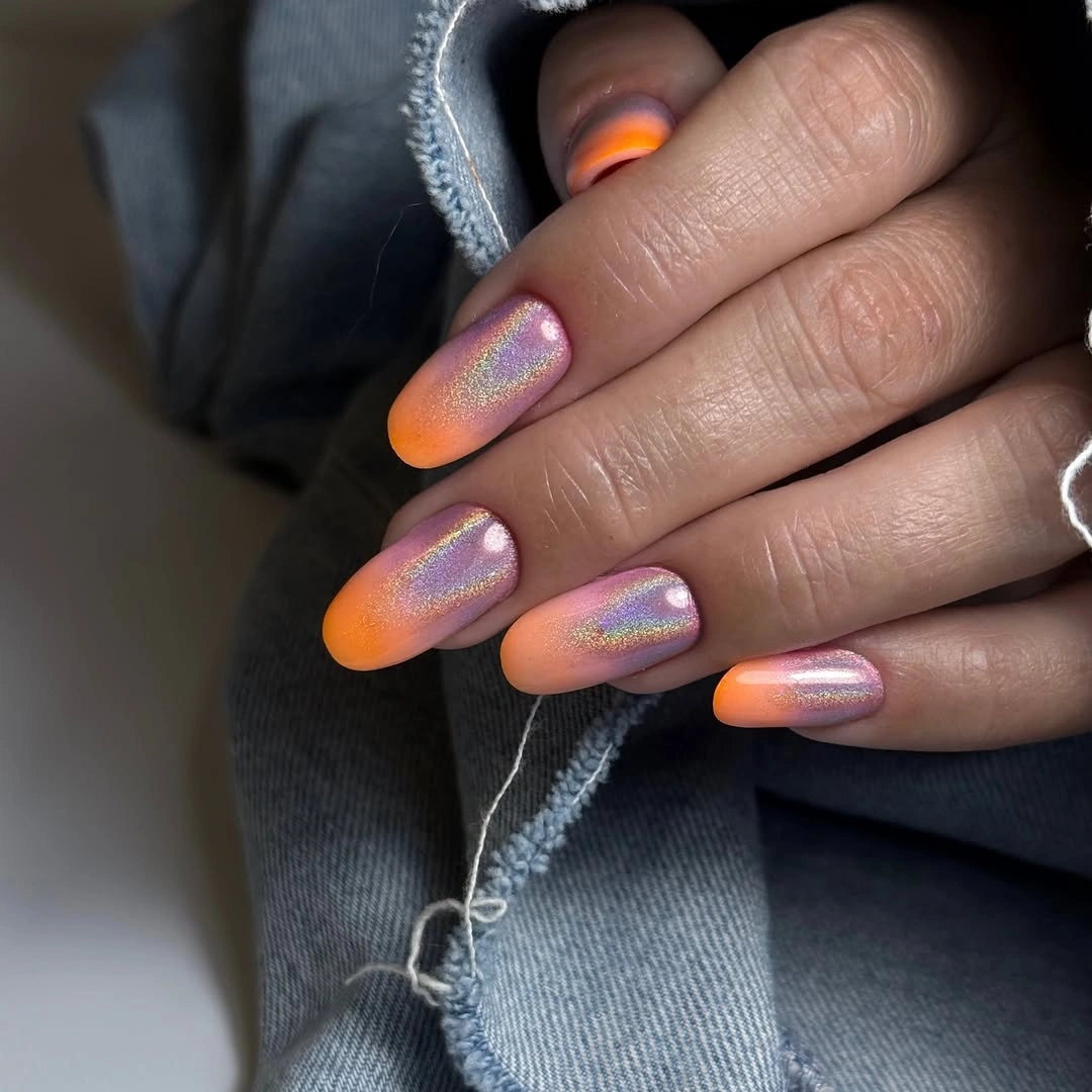 Almond nails with iridescent pink base and warm tip flashes