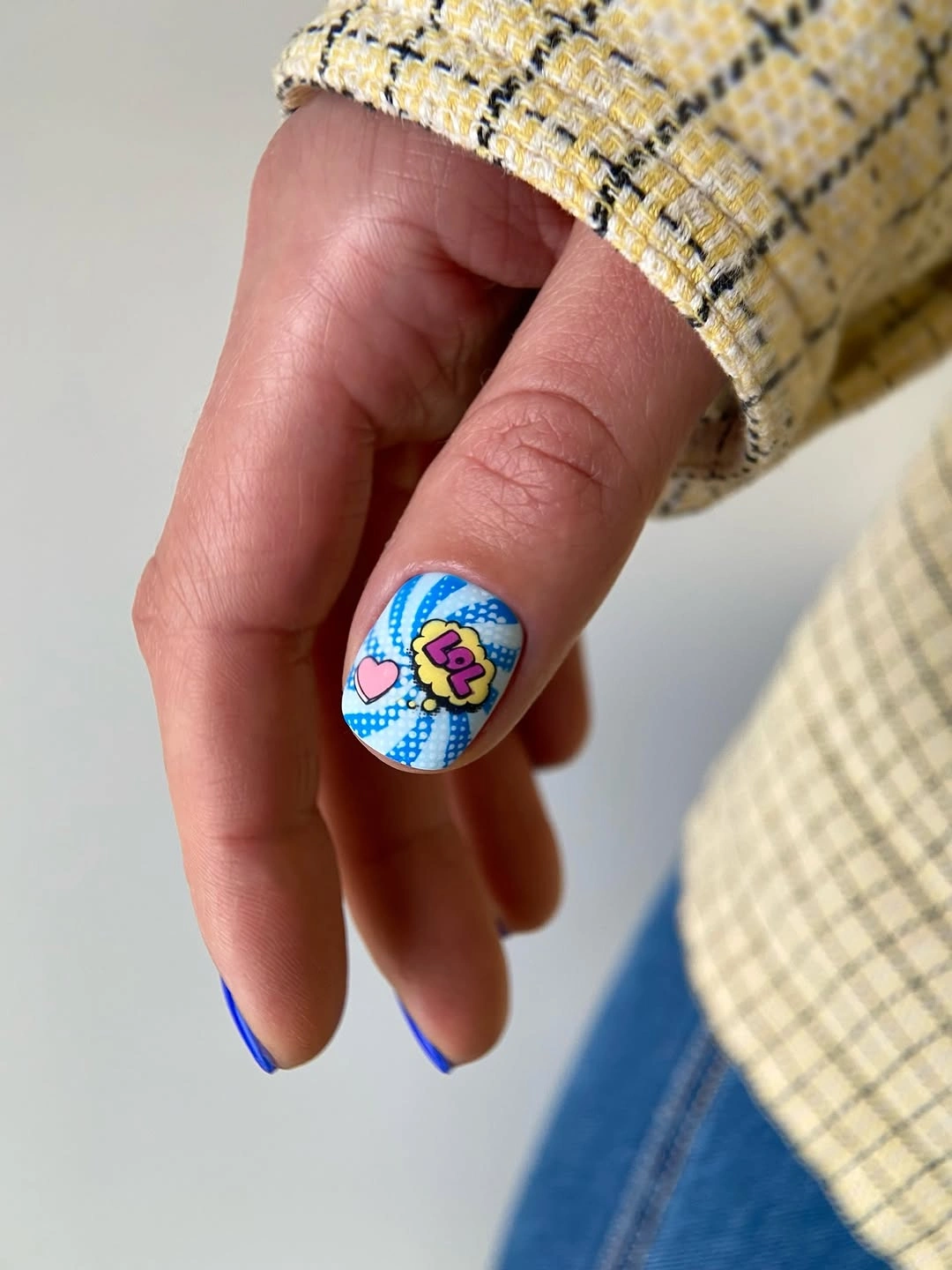 Short blue nails with one colorful illustrated accent