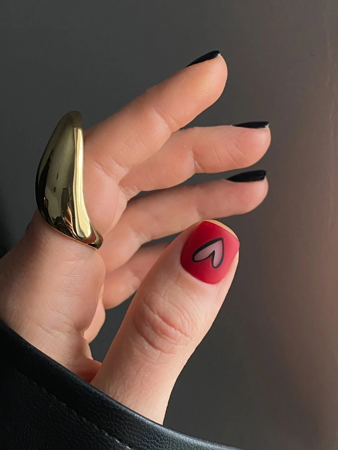 Nude almond nails with black tips and one red accent