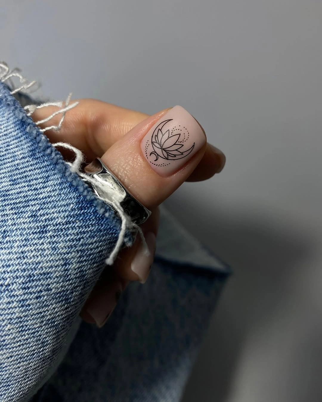 Short nude nails with one tiny black botanical accent