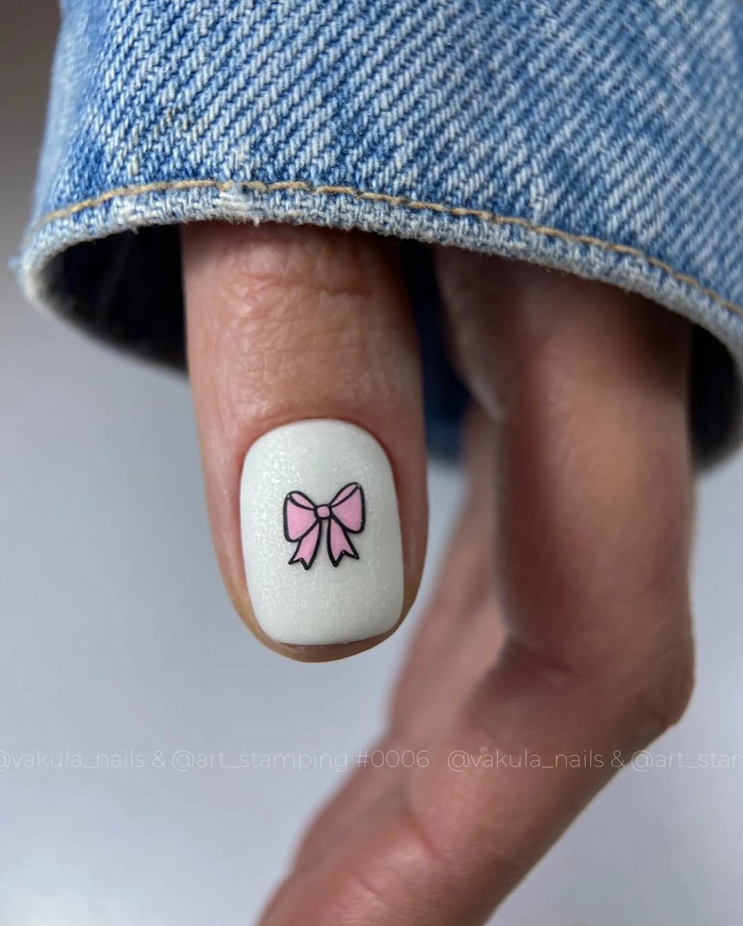Cream rounded-square nails with one pink bow accent