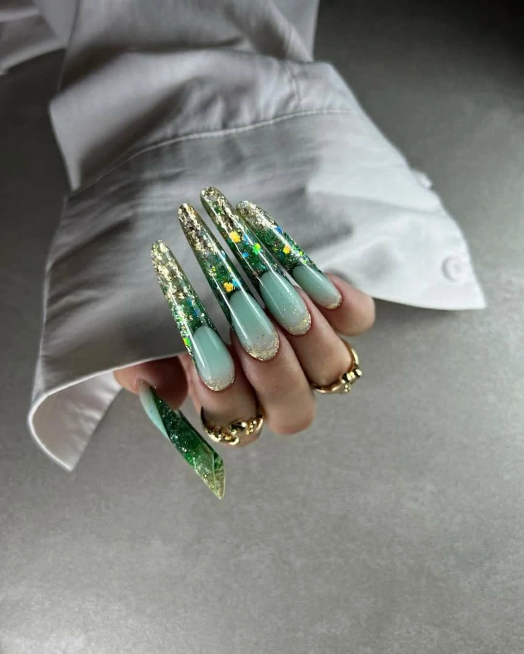 Long mint green nails with dark green and gold accents