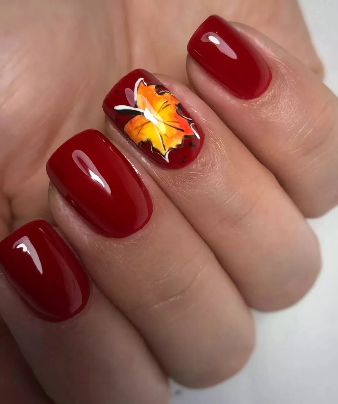 Short burgundy square nails with one warm floral accent