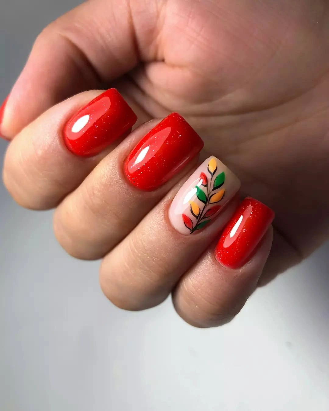 Bright red square nails with one cream botanical accent