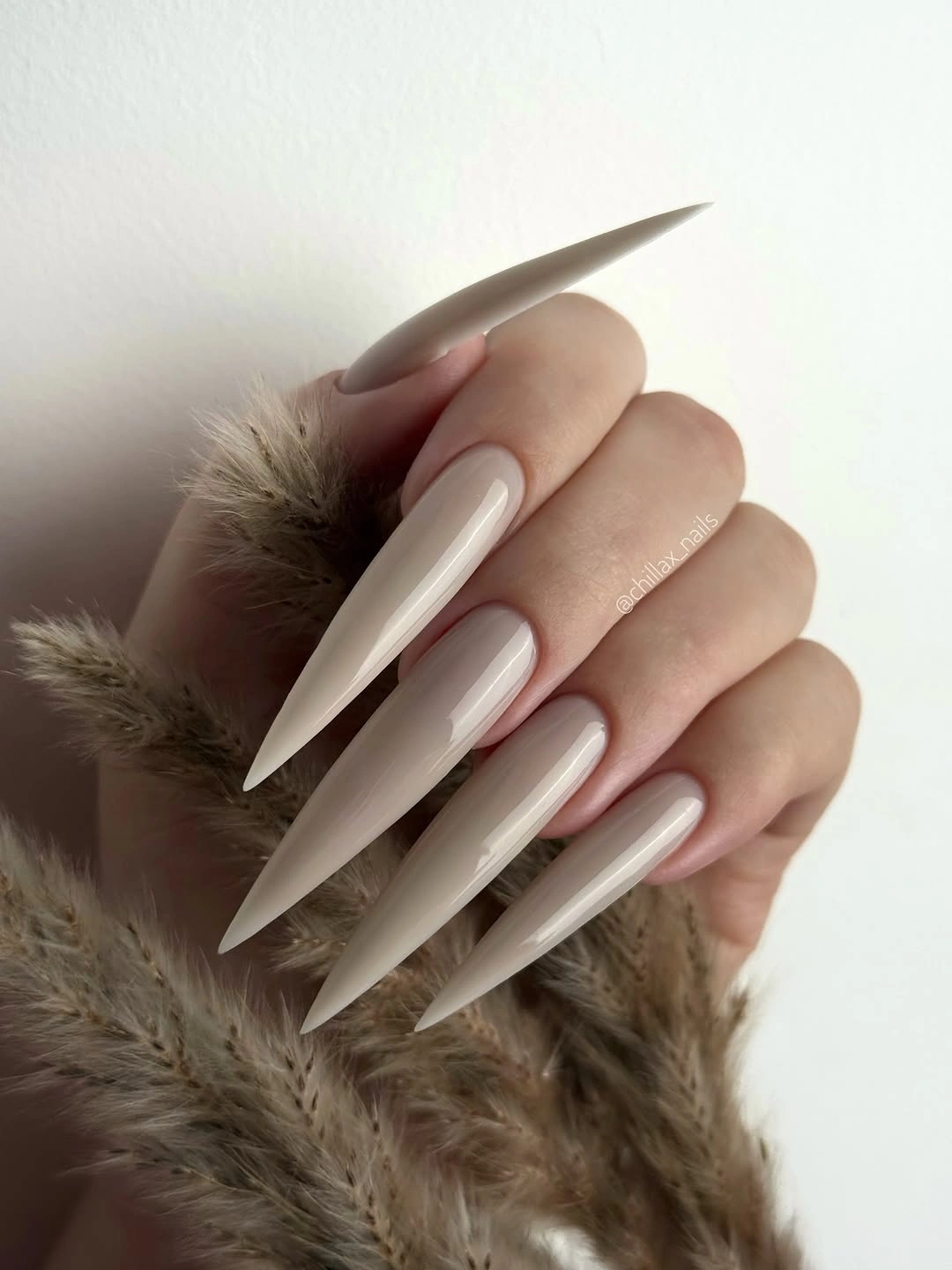 Very long pale milky nude stiletto nails with subtle detail