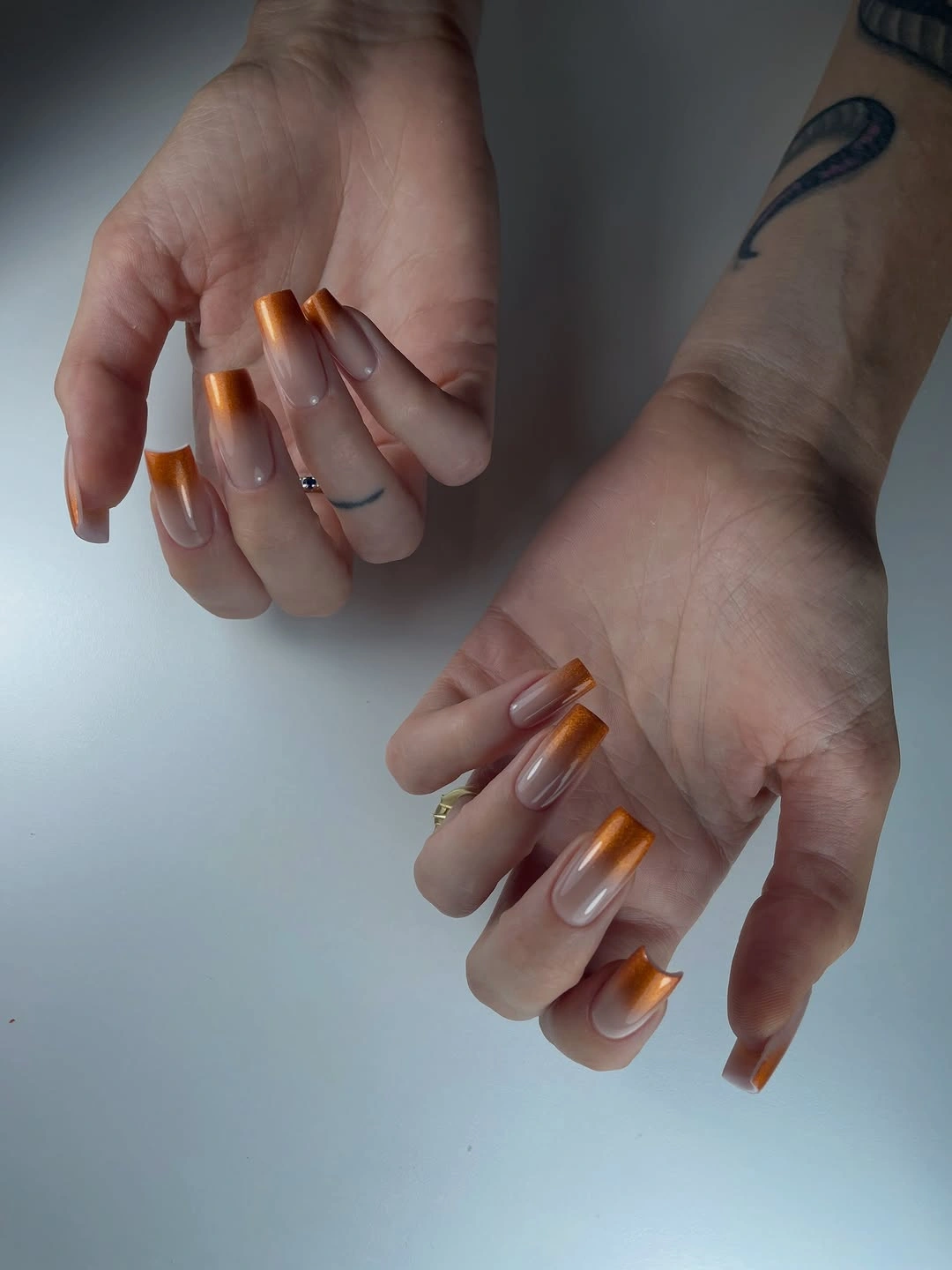 Long almond nude nails with focused amber orange glossy accents