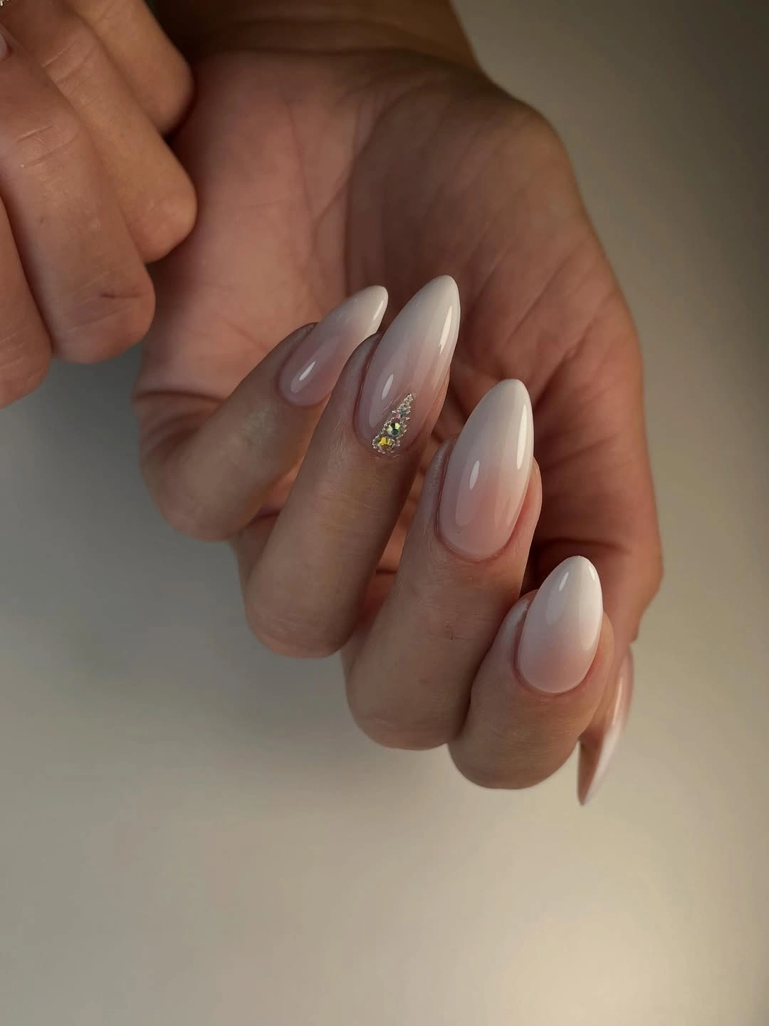 Medium almond nails in a glossy milky nude finish
