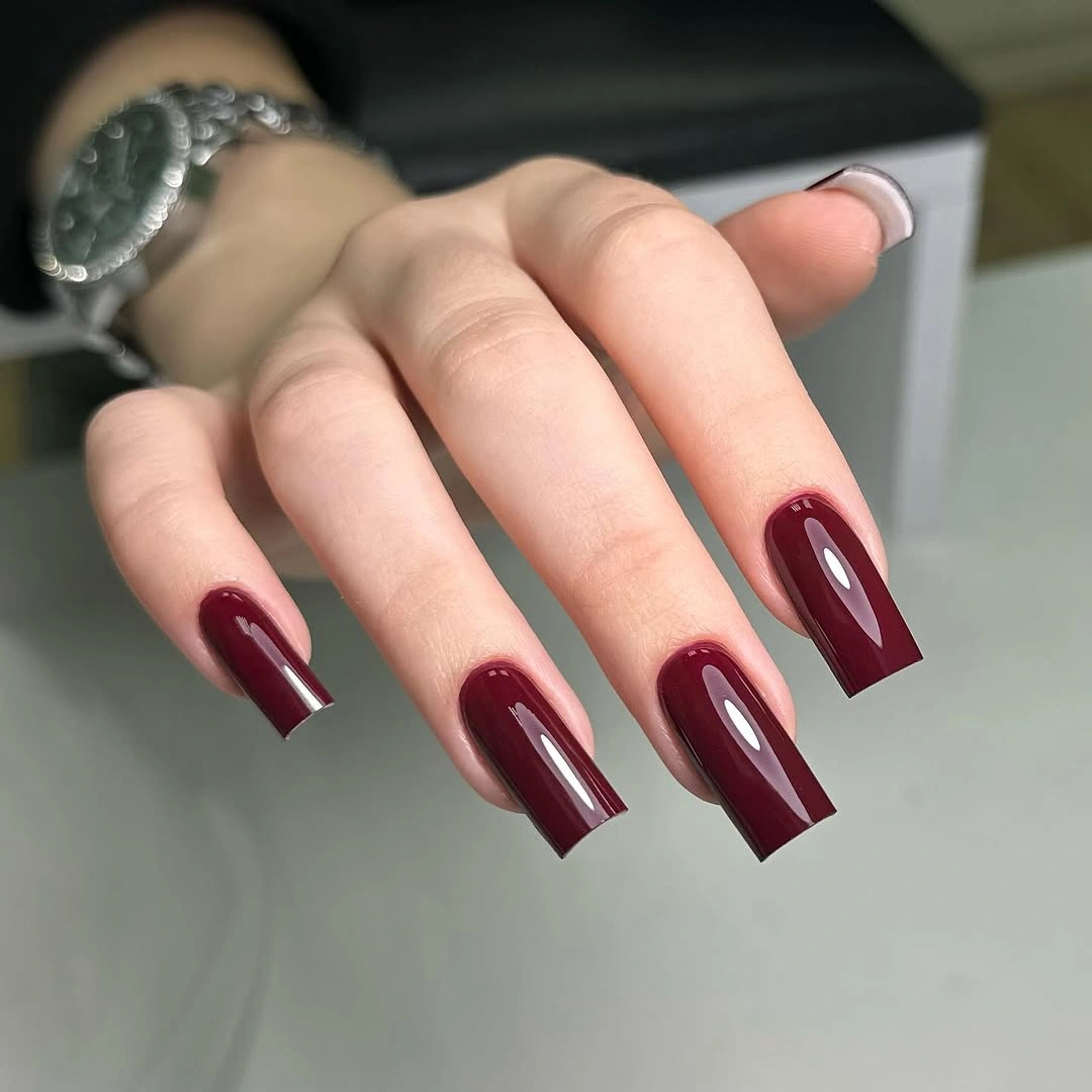 Long square burgundy nails with repeated pale curved lines