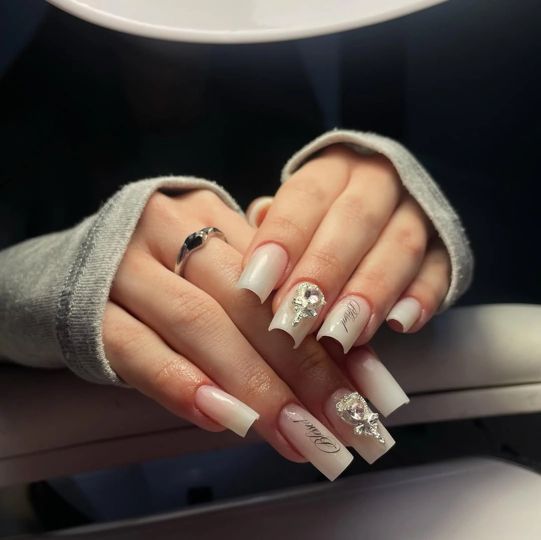 Long square pale pink nails with white floral and silver accents