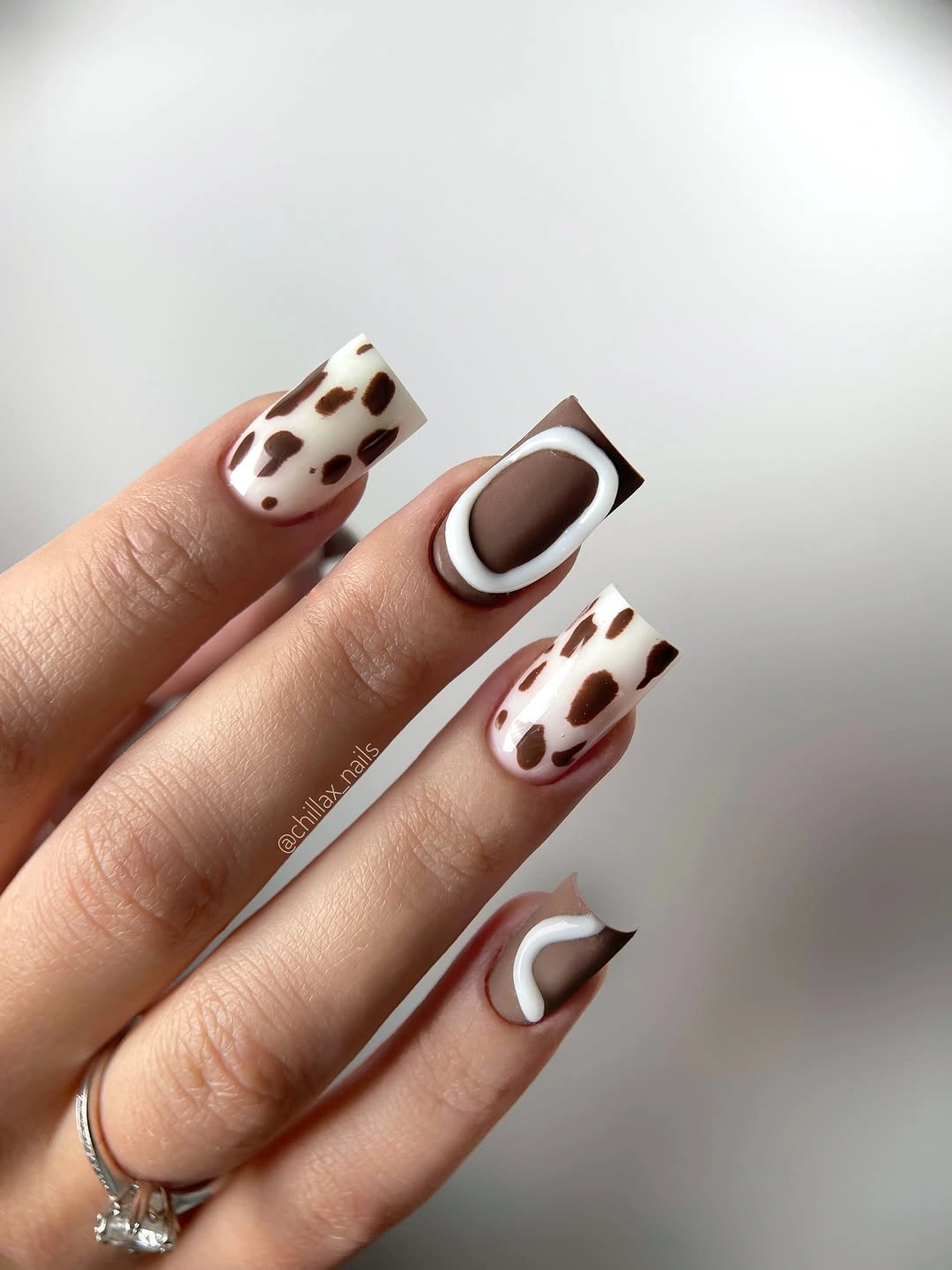 Milky almond nails with brown spotted animal-style accent nails