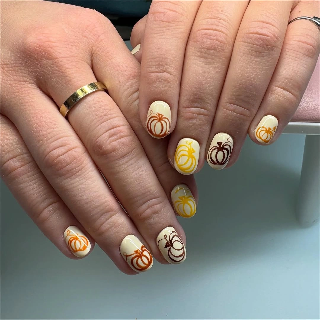Short rounded white yellow nails with simple pumpkin line drawings