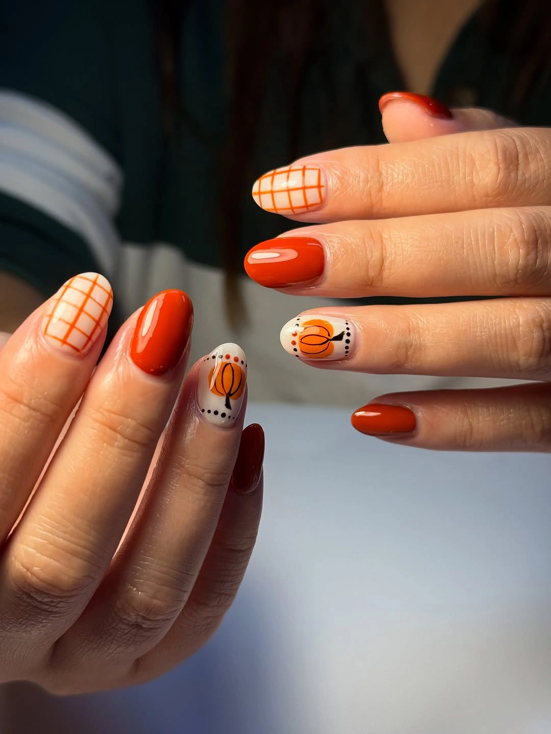 Short rounded orange red nails with checkered pumpkin accents