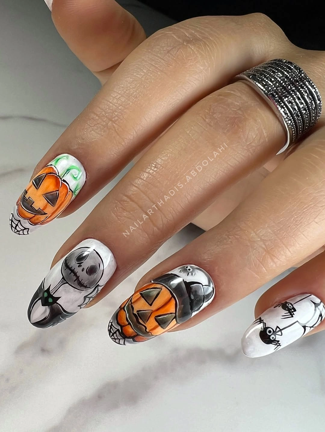 Long almond pale nails with black botanical lines and one orange pumpkin accent