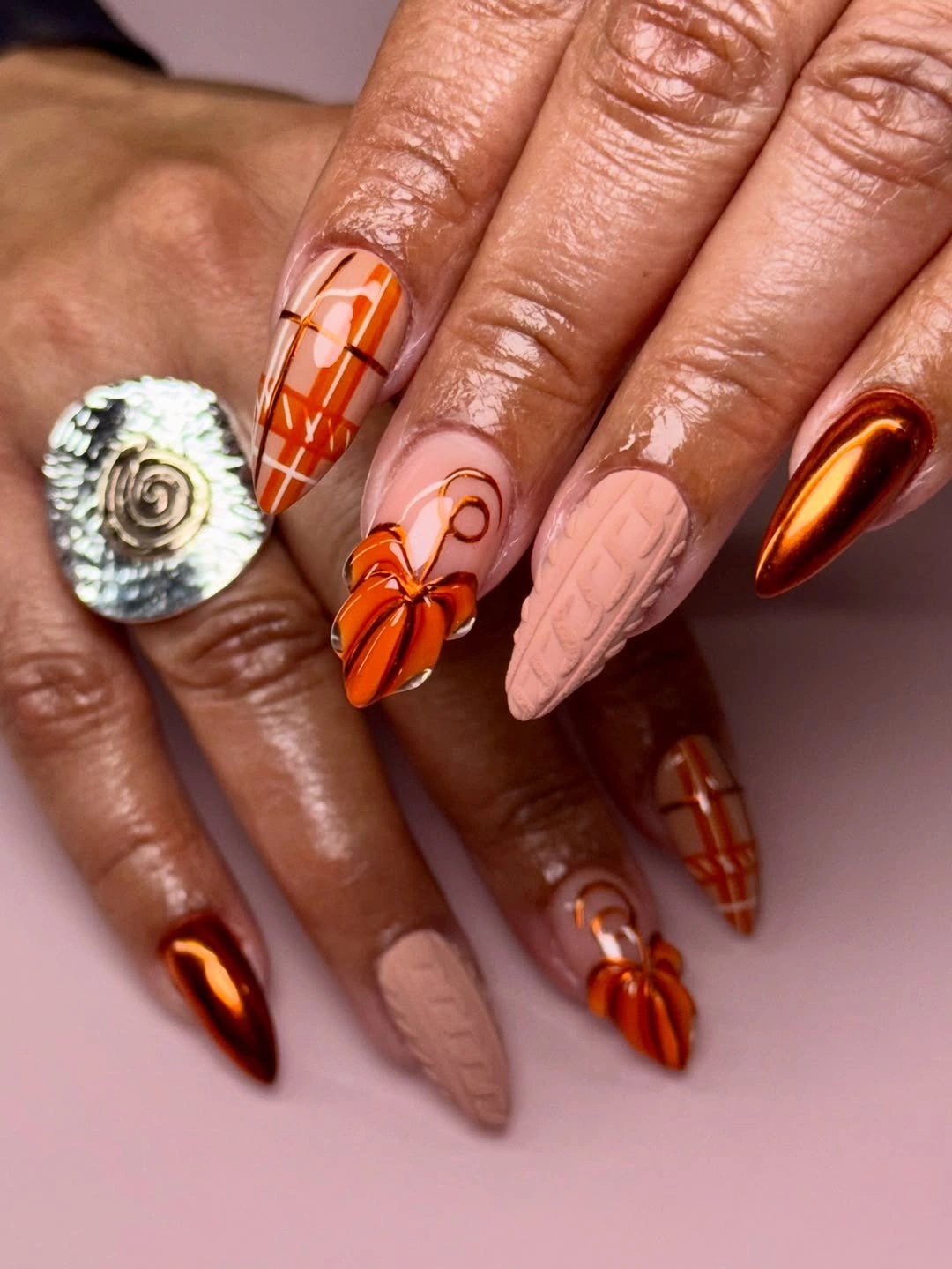 Very long coffin nails with orange pumpkin linework and warm neutral bases