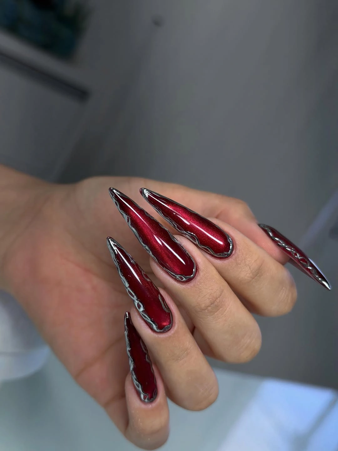 Dark red stiletto nails with chrome-like edges