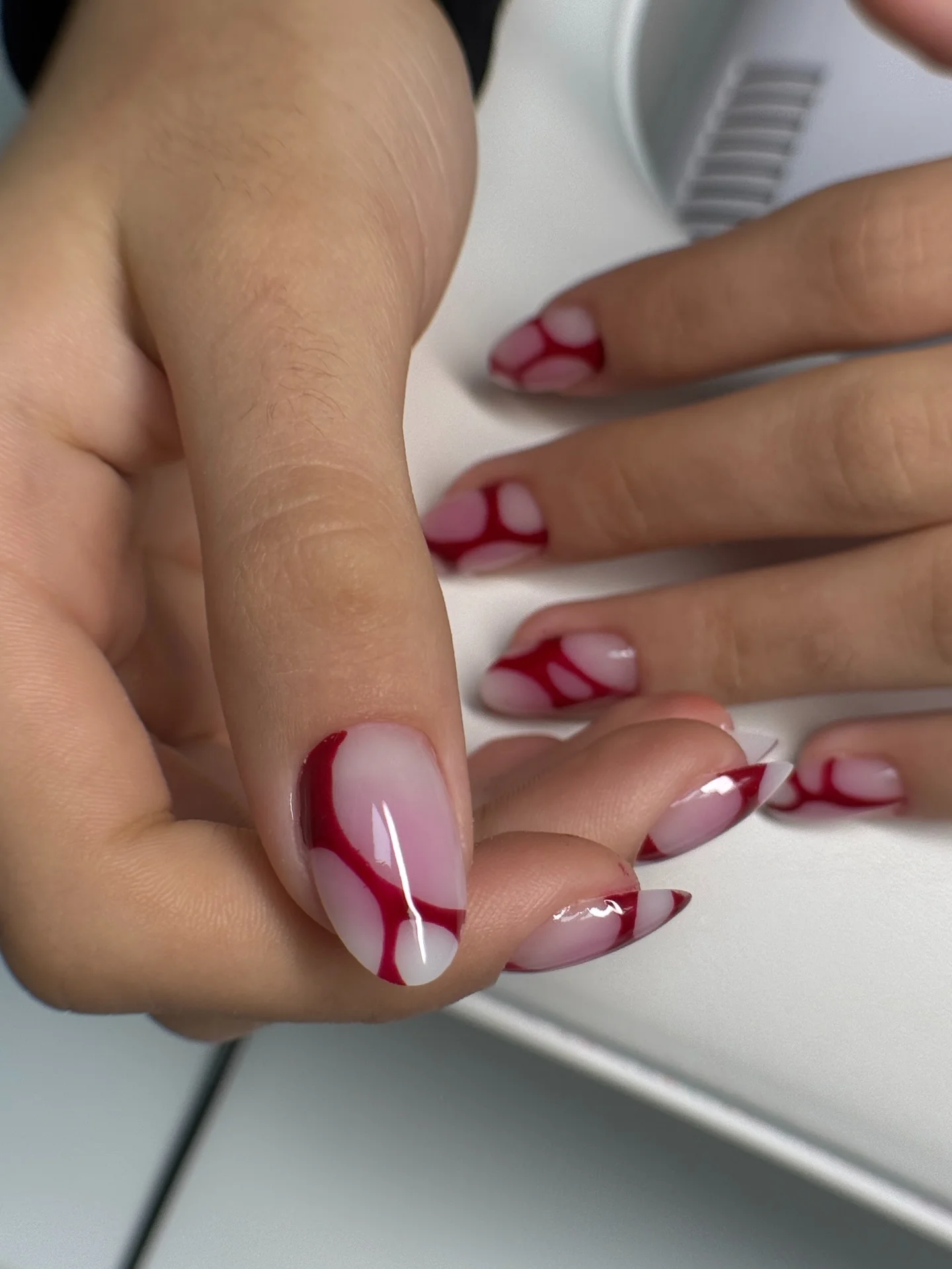 Short red negative-space nails on sheer pink