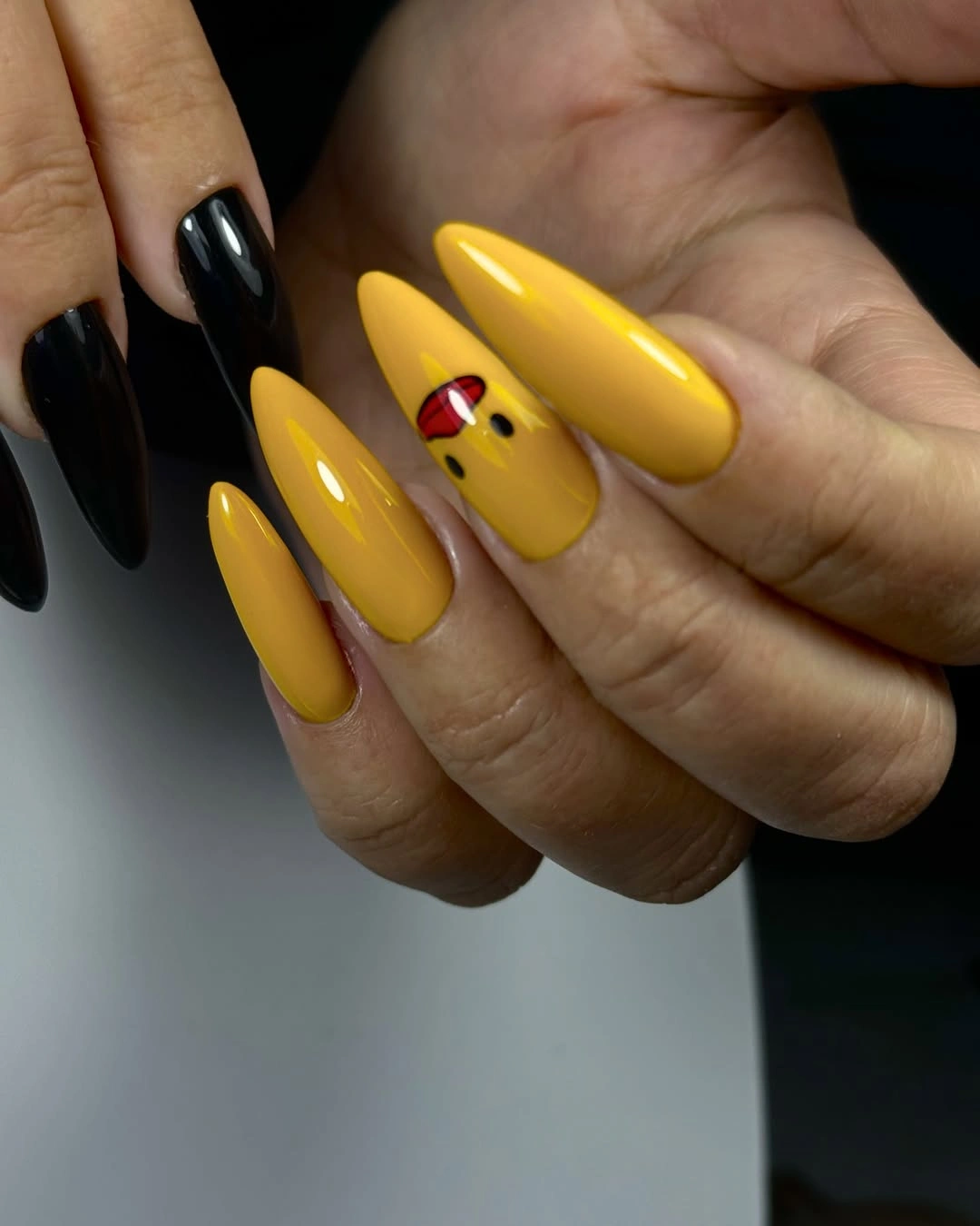 Long almond nails with glossy mustard yellow and one black red accent