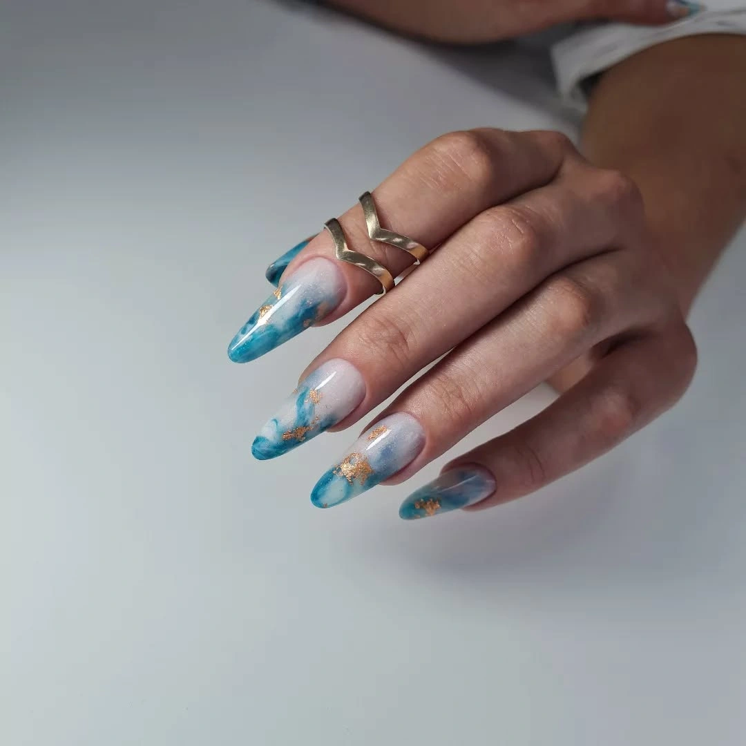 Long almond nails with sheer white base and watery blue abstract edges