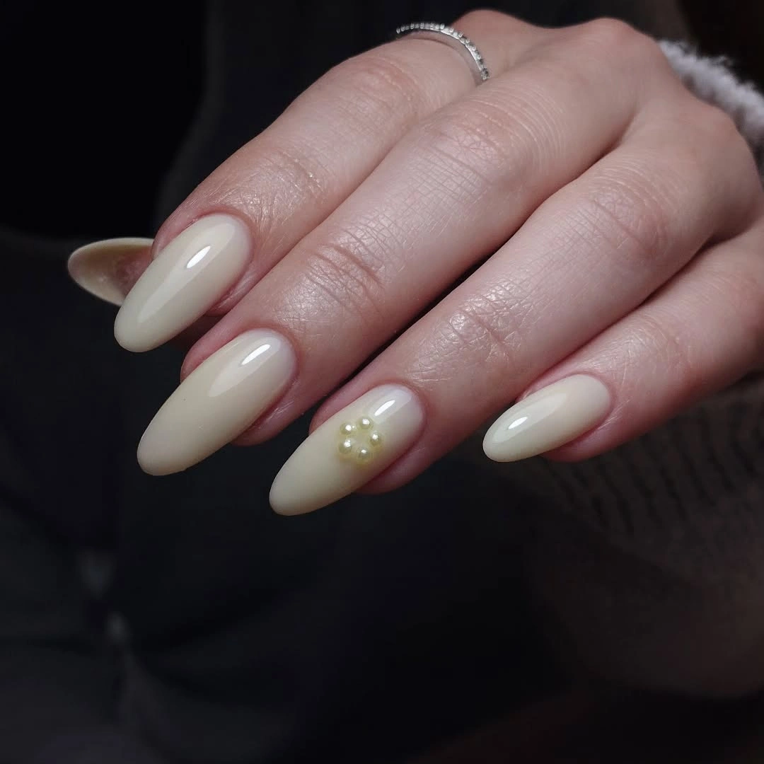 Medium almond nails with sheer blush base and tiny gold accents