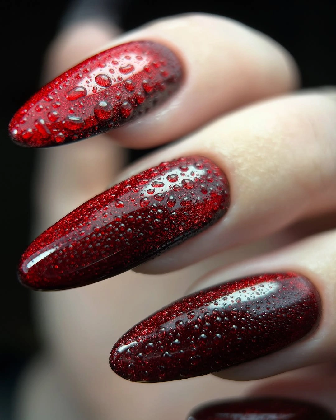 Medium almond nails in deep red with dense textured sparkle