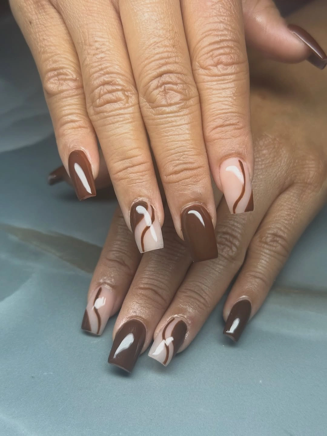 Brown and pale pink square nails with white curved accents