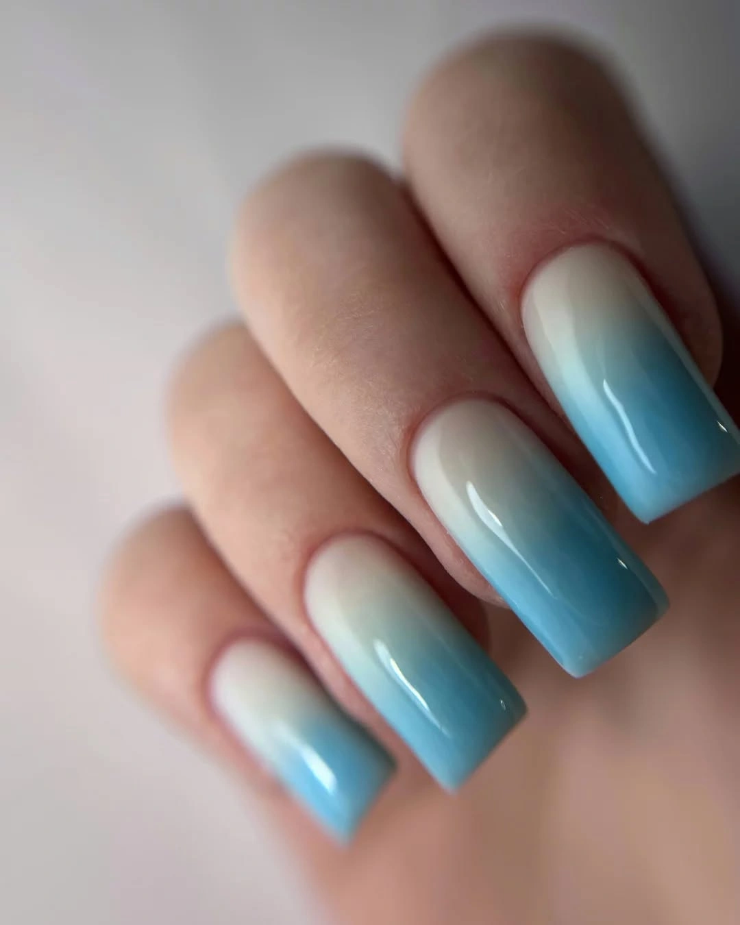 Long square nails fading from milky white into sky blue