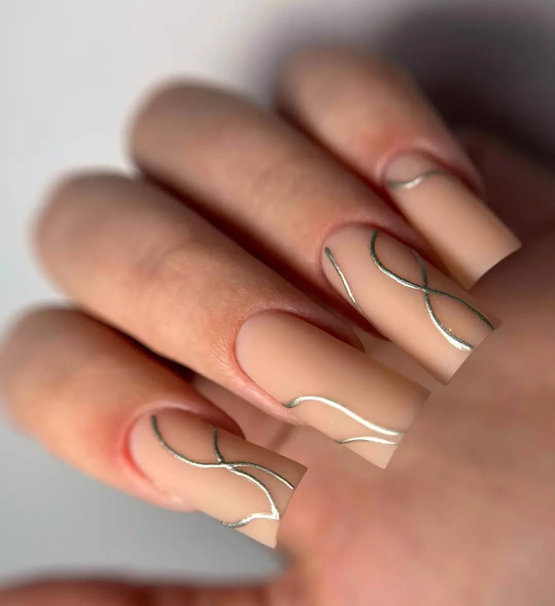 Long nude square nails with thin silver wave lines