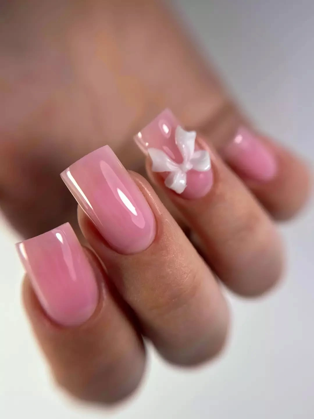 Glossy pink long square nails with one white flower accent