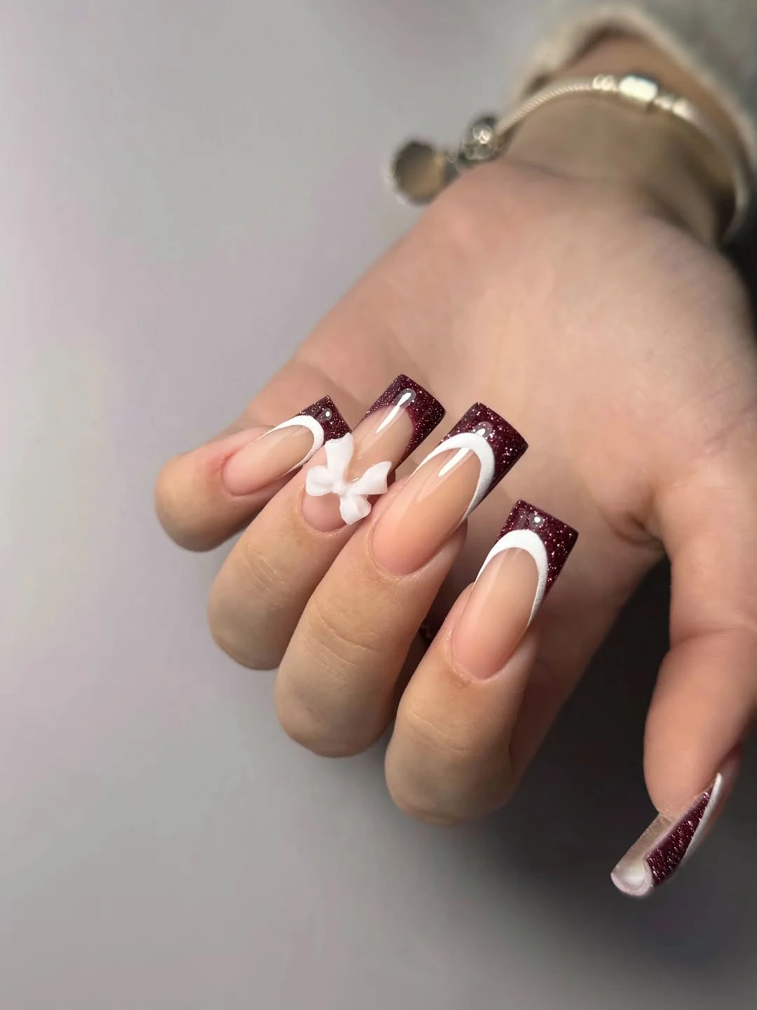 Long square nude nails with burgundy glitter French tips