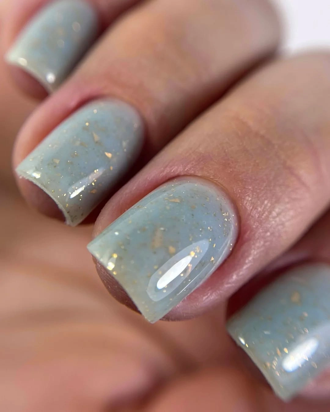 Short icy blue square nails with delicate gold flakes