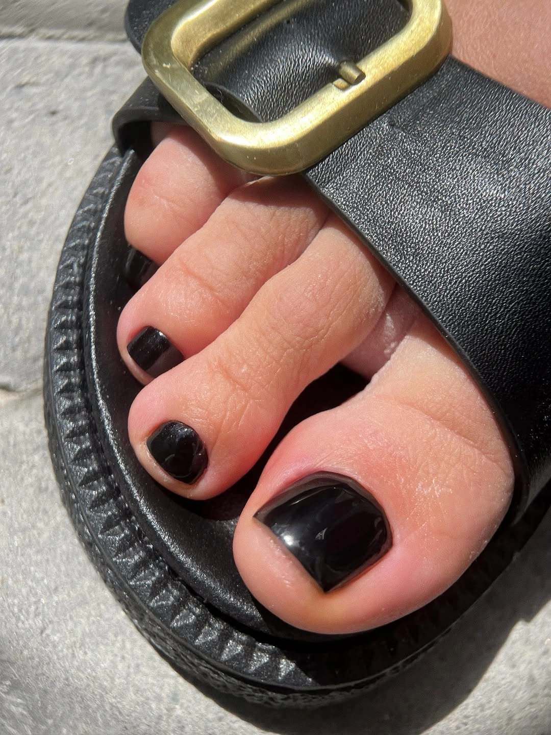 Glossy black short square toenails in black sandals