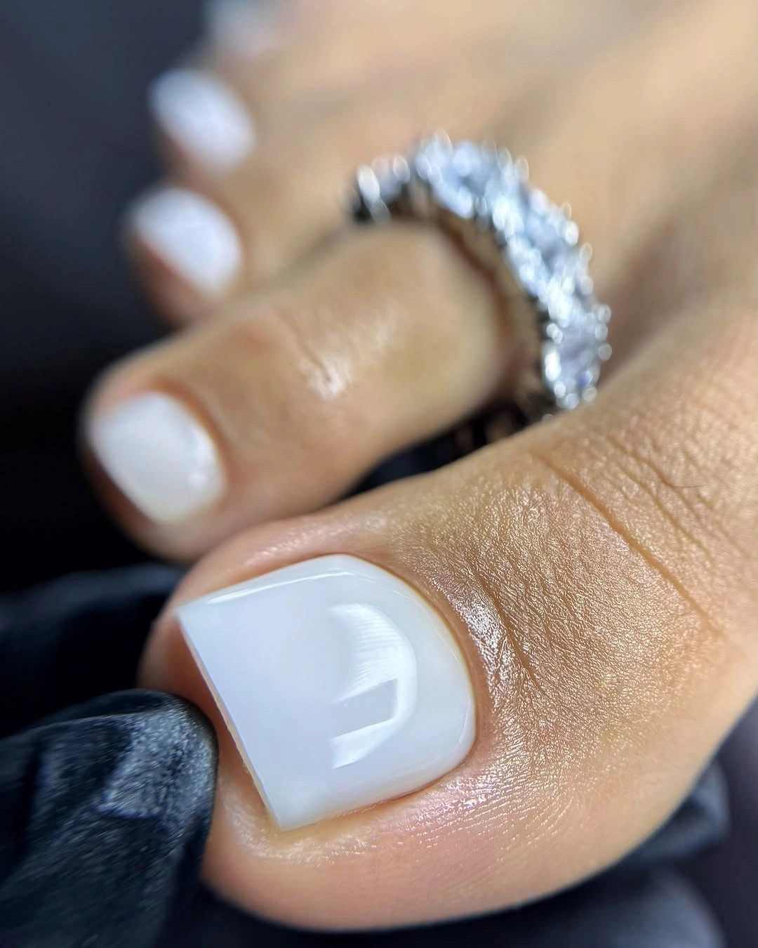 Opaque white short square toenails with nearby silver accessories