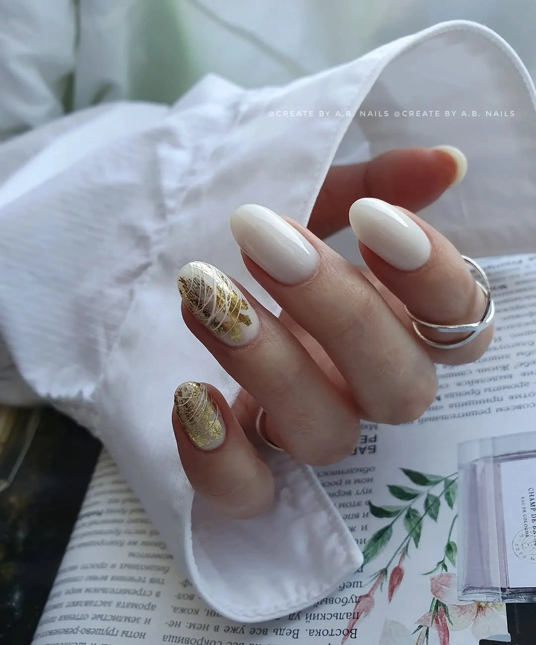Short oval milky white nails with sparse warm metallic accents