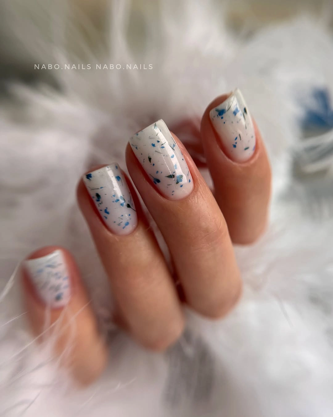 Milky white short square nails with small blue gray flecks