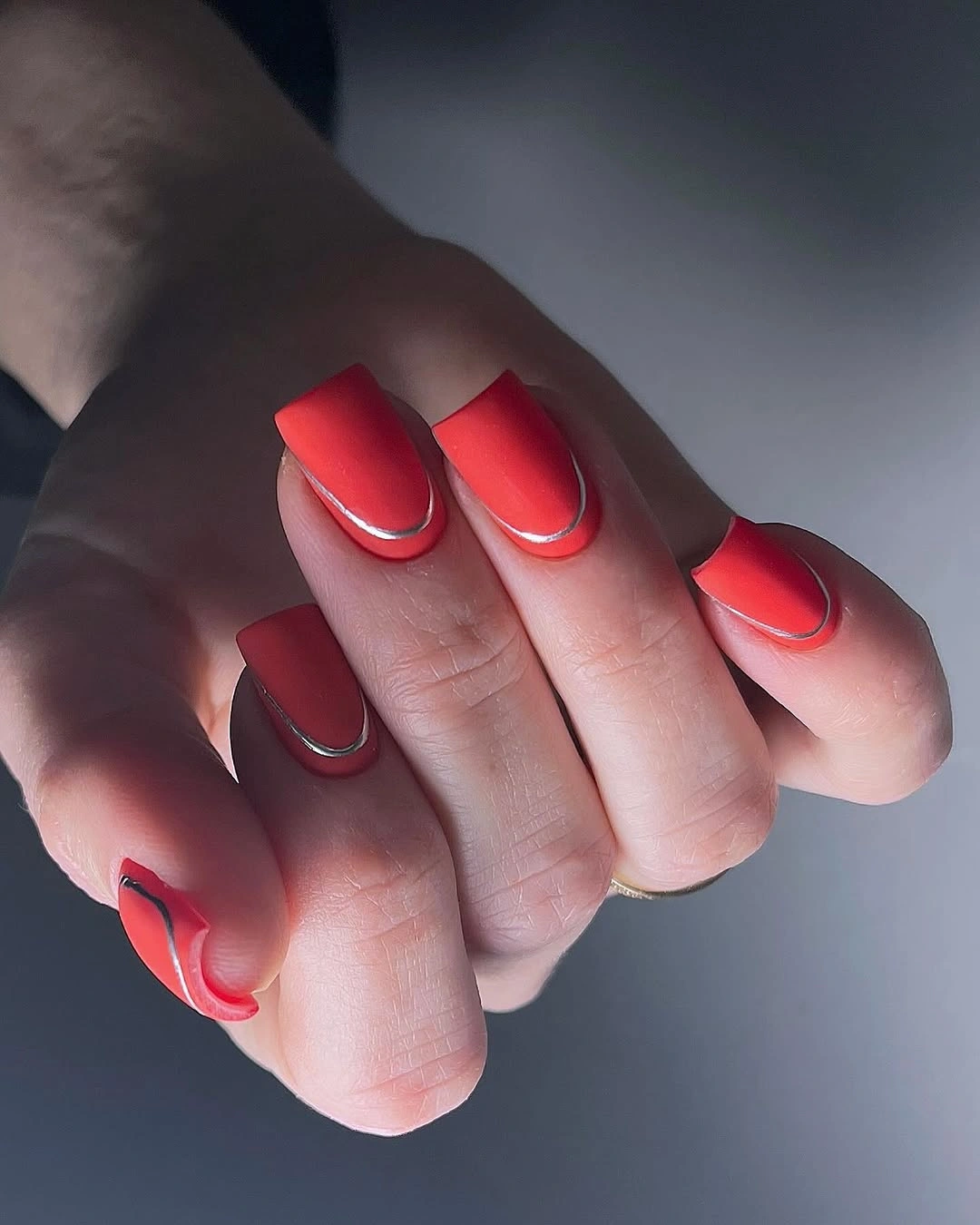 Short coral red nails with a thin bright edge detail