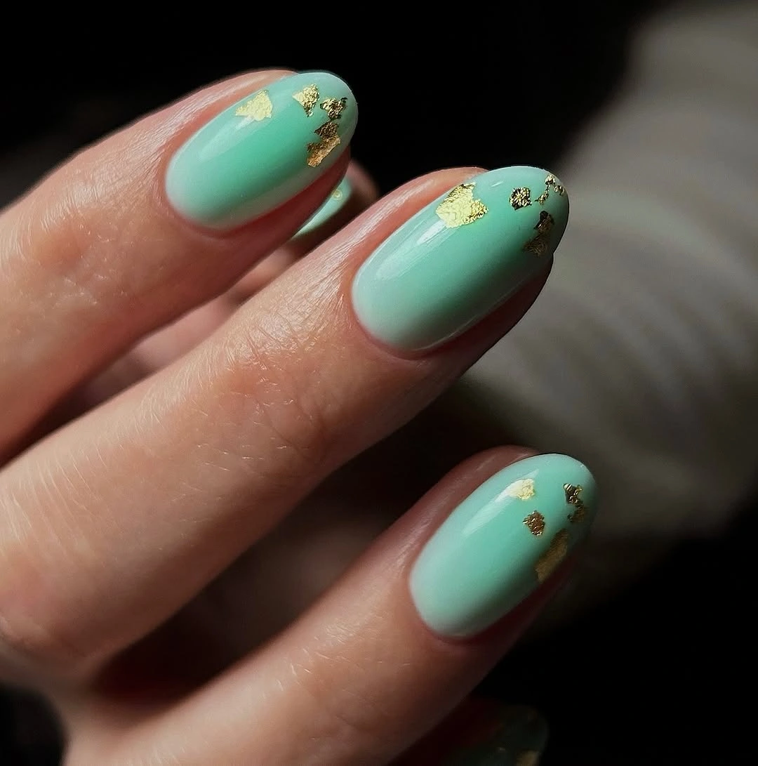 Short mint oval nails with small irregular gold accents