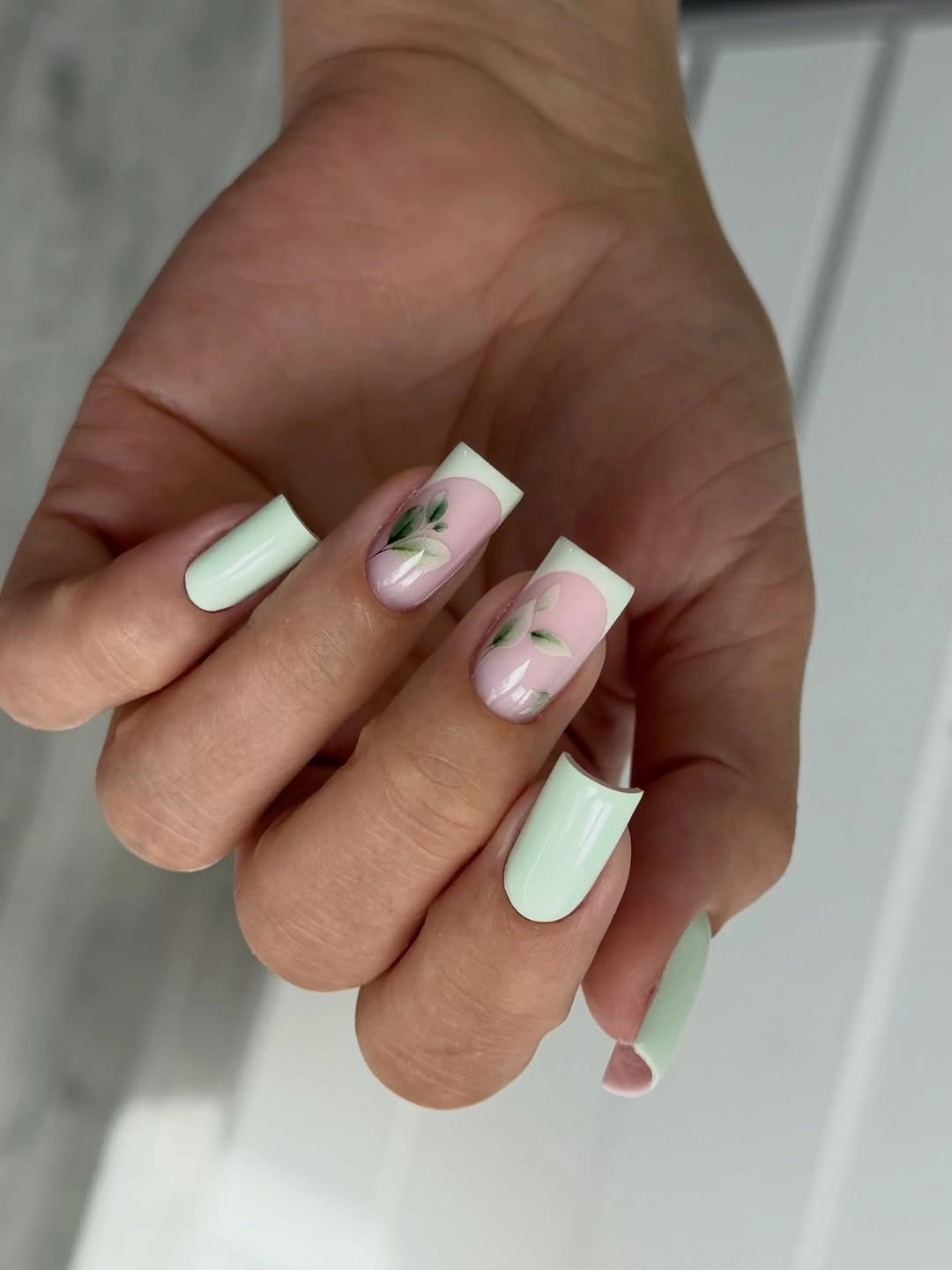 Pale mint square nails with white edges and botanical accents