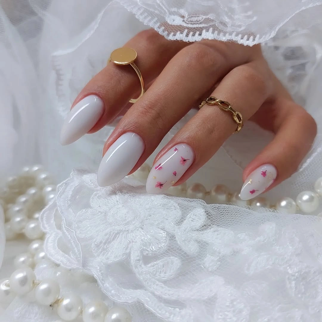 Milky almond nails with tiny floral flecks and gold